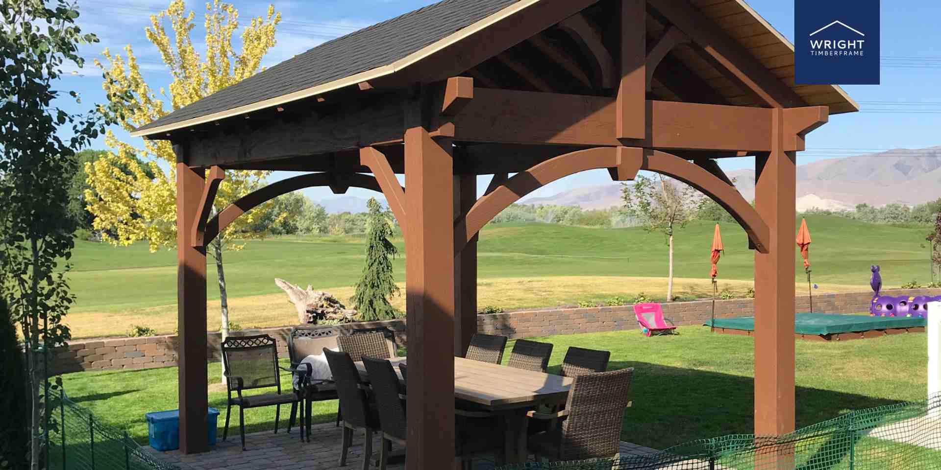Timber Pavilion Built by Pergola Builder in Utah Pergola builder Utah project featuring a custom timber pavilion with outdoor dining space set against a scenic green landscape