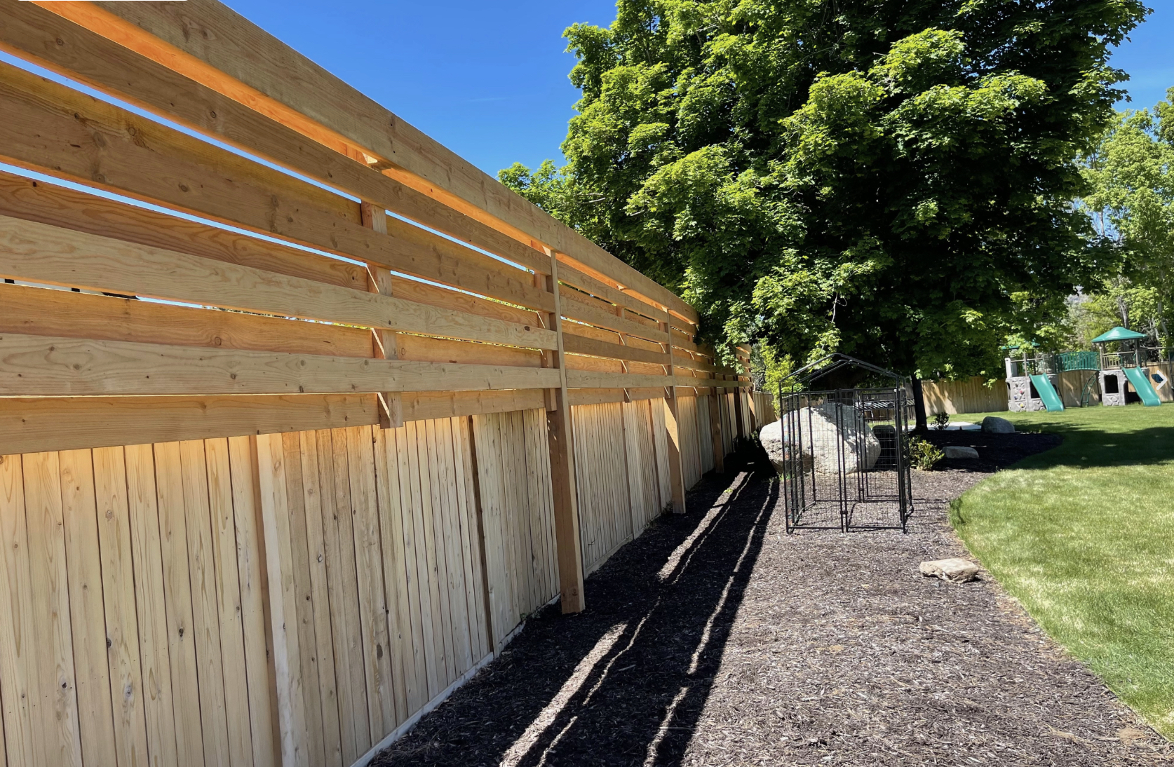 Tall wood trellis fence in a landscaped yard showing the purpose of trellis in adding privacy, structure, and support for climbing plants