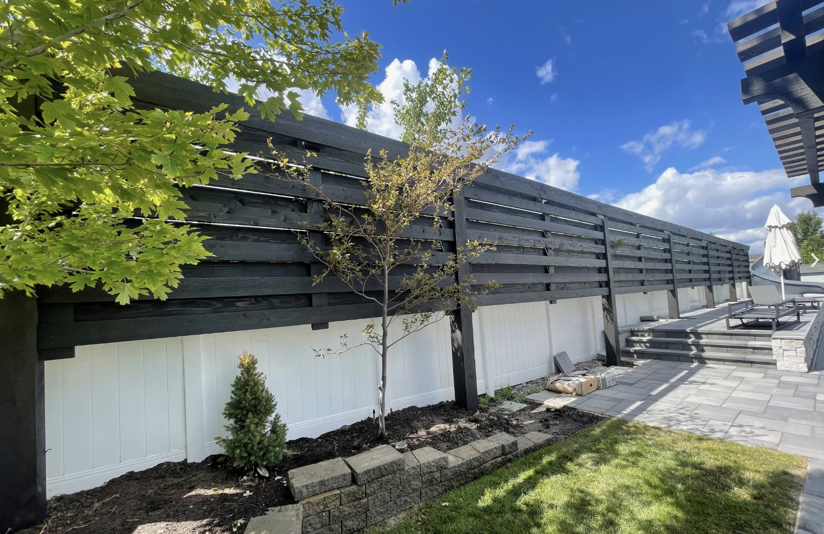 Modern Custom Wood Trellis Privacy Screen Modern custom wood trellis adds privacy along a patio, dark slats above white panels with trees and lounge seating