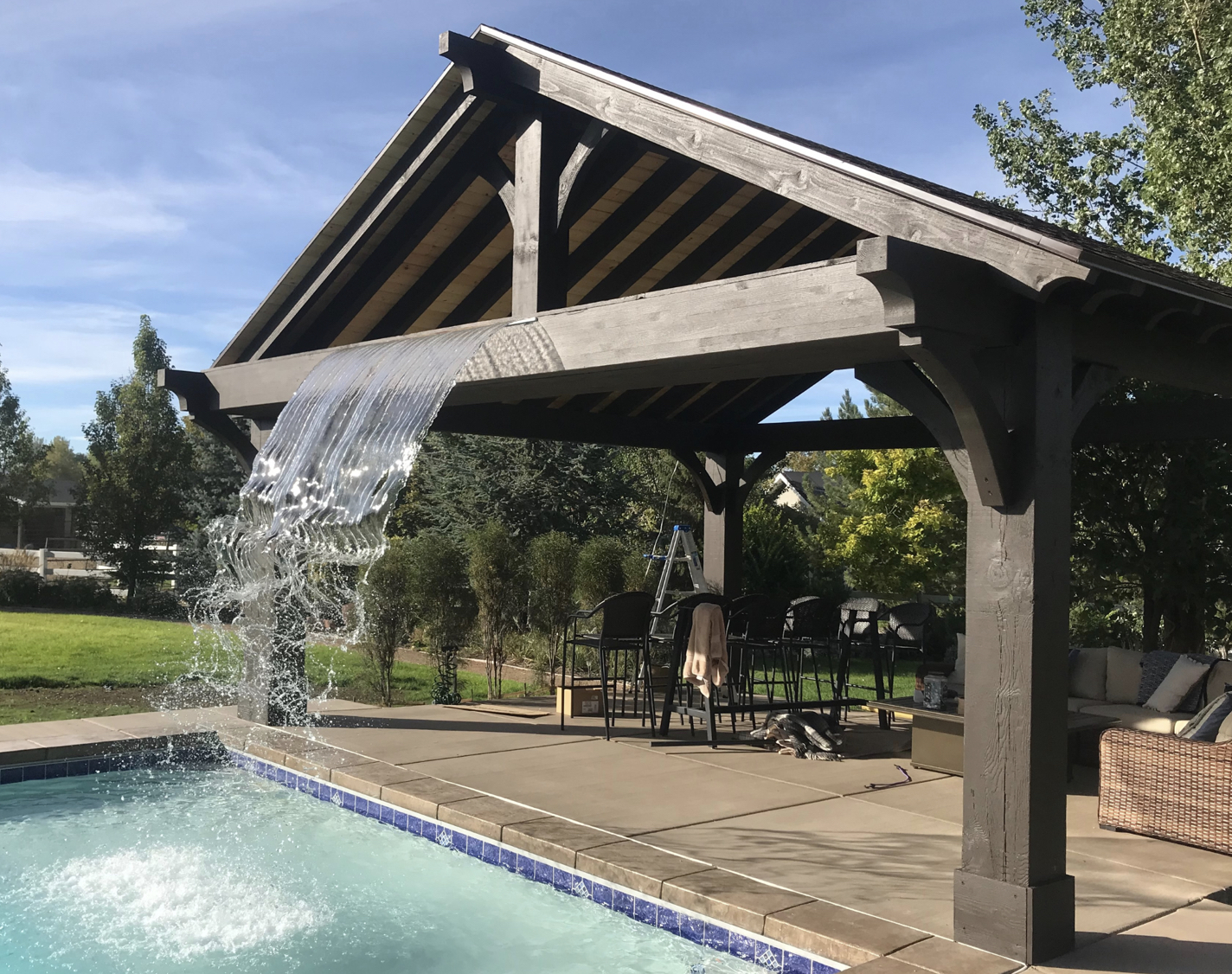 Timber pavilion featuring a built-in waterfall over a pool, showcasing creative and luxurious pavilion design ideas for outdoor living