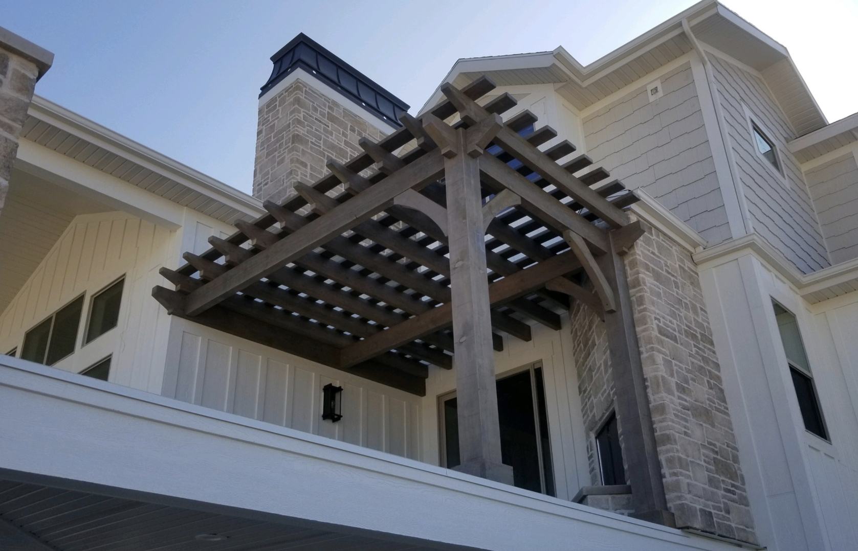 Timber pergola on upper level, attached; braced posts and beams show stability; are freestanding pergolas safe.
