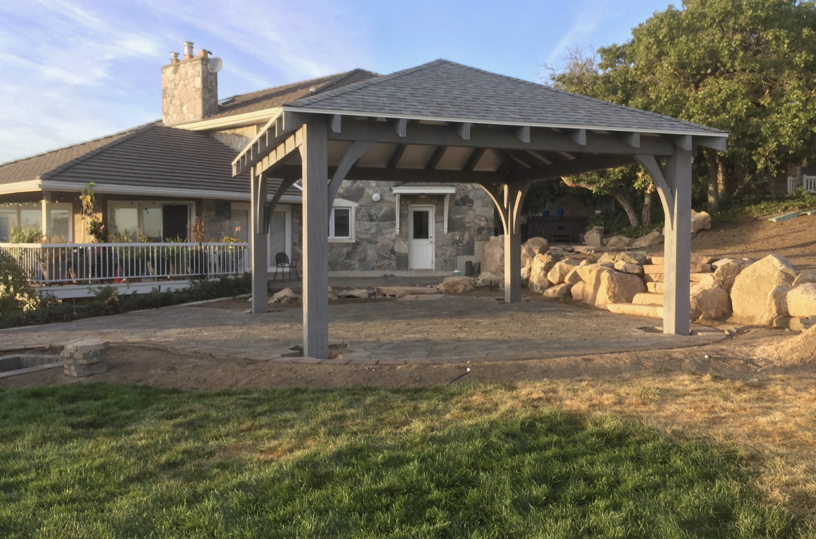 Backyard Pavilion with Gray Timber Frame Gray timber frame outdoor pavilion with hip roof set on stone patio, highlighting functional outdoor pavilion designs.