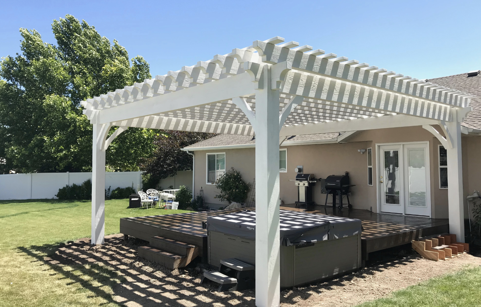 Timber frame pergola in backyard with hot tub and outdoor seating, showcasing premium wood craftsmanship and traditional design elements.