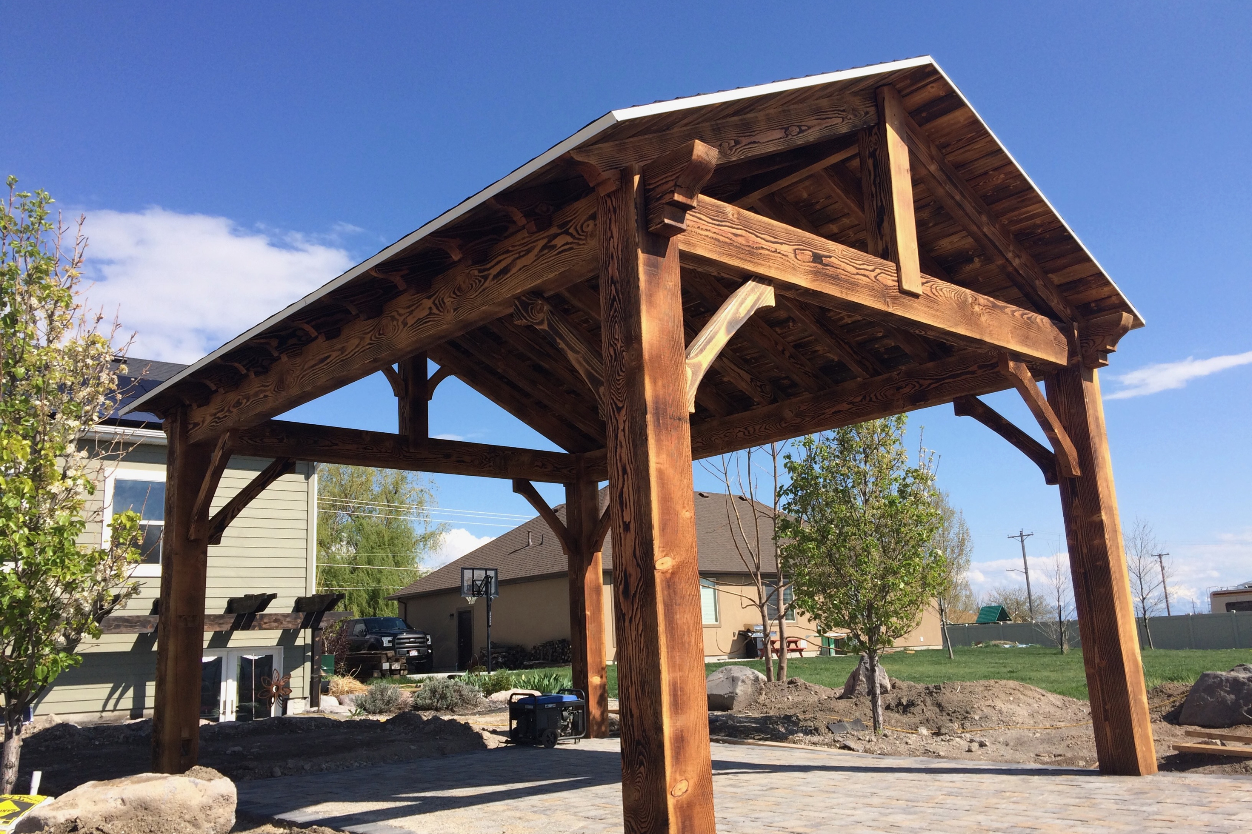 Charred hickory timber frame pavilion in a Utah backyard, open post-and-beam design.
