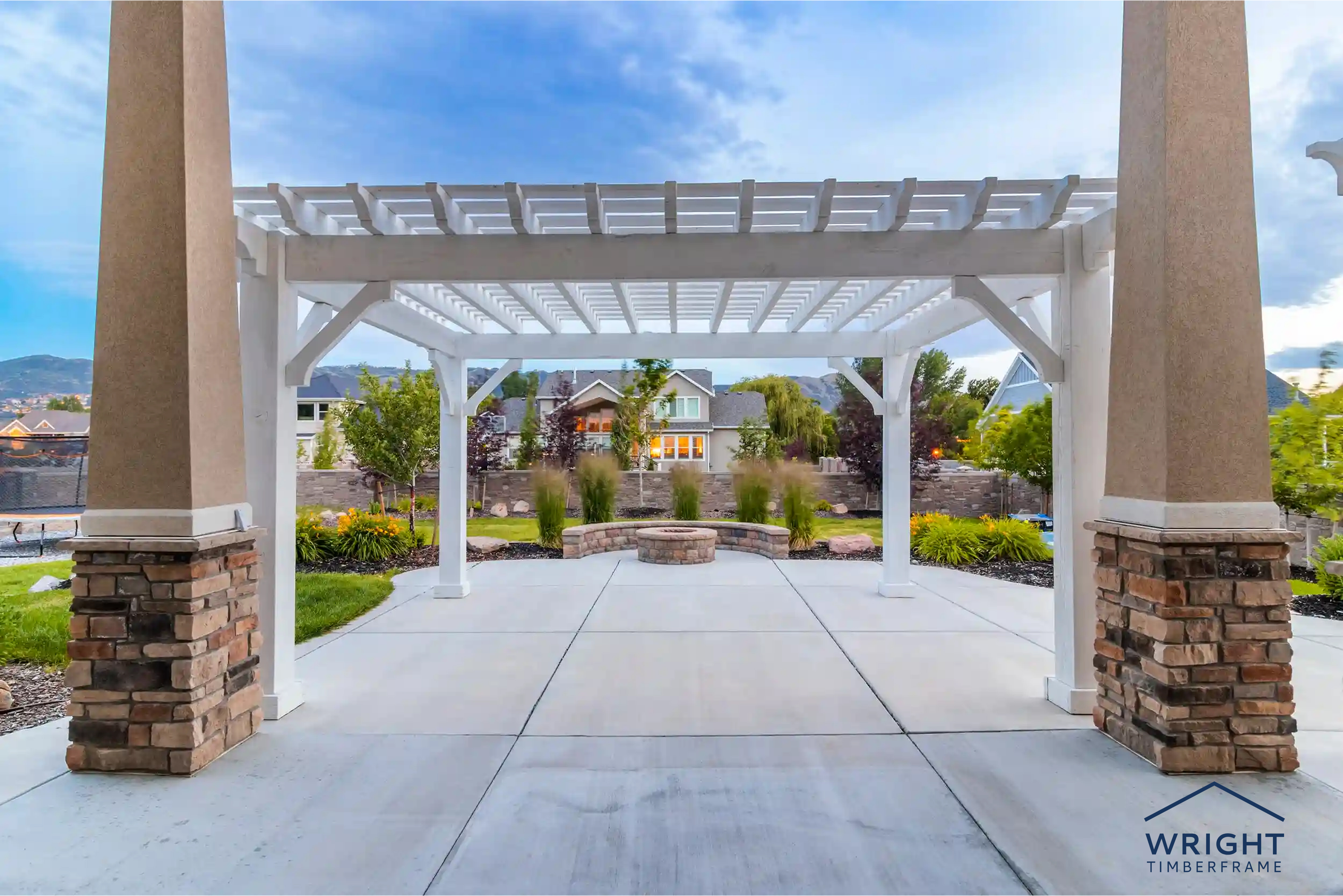 Buy a Pergola in Winter for Better Value White backyard pergola over a patio with landscaped garden, highlighting why homeowners choose to buy a pergola in winter.