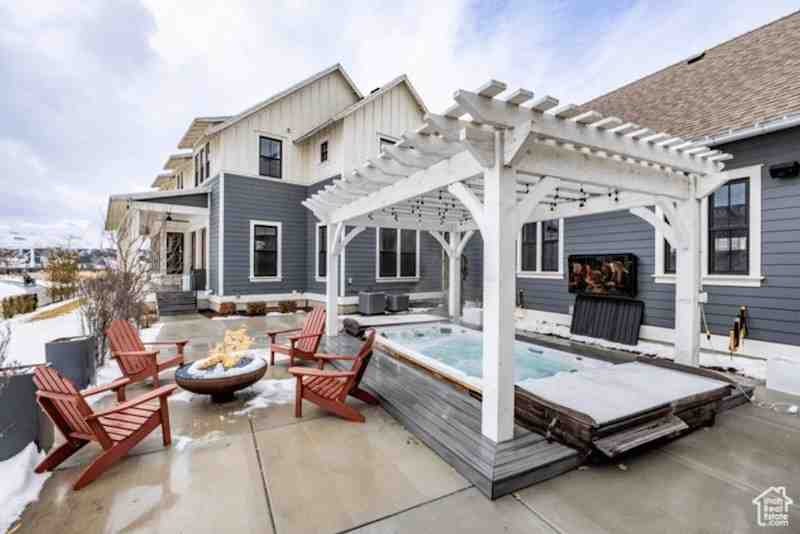Hot tub pergola cover with white timber frame over outdoor spa area featuring seating, fire pit, and modern backyard design