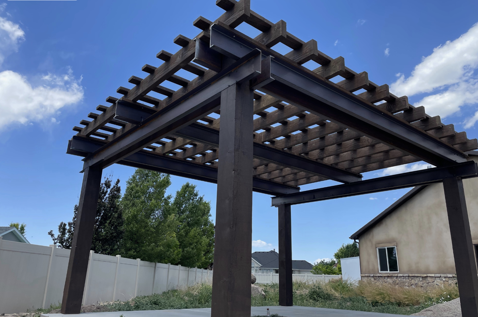 Pergola color selection showing modern timber pergola with dark wood finish in backyard setting under blue sky with clean structure lines