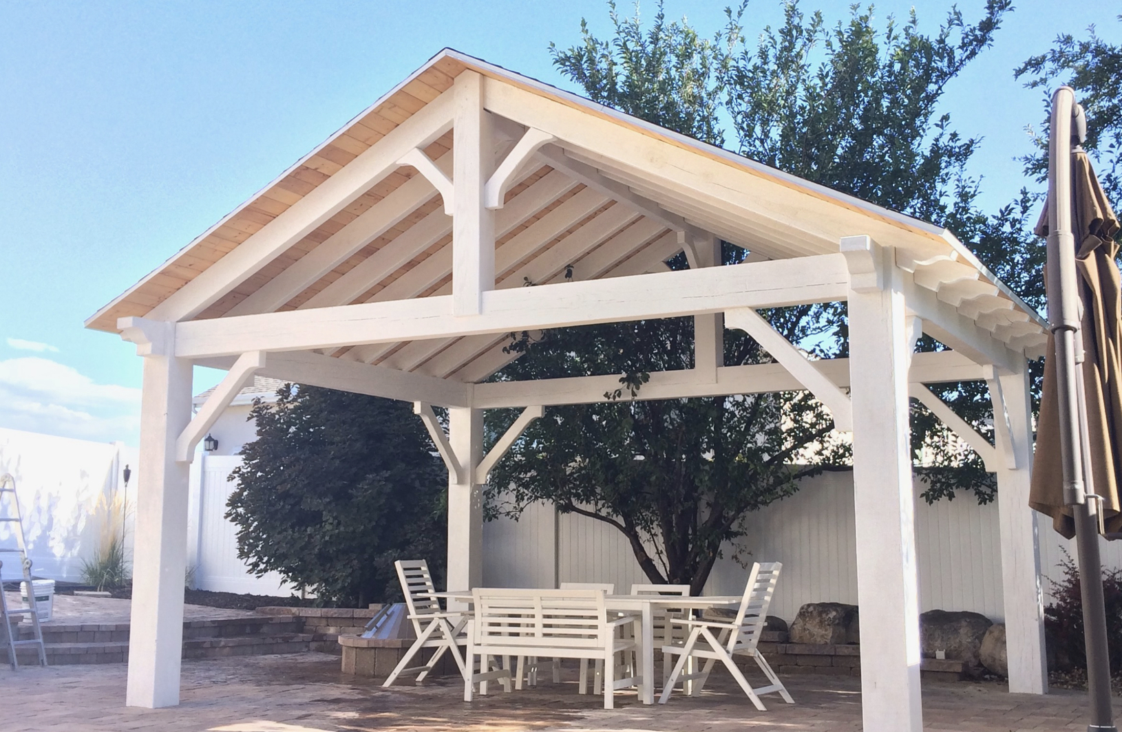 Pavilion vs Gazebo example showing white timber pavilion with open sides, gable roof, and outdoor dining setup in backyard patio
