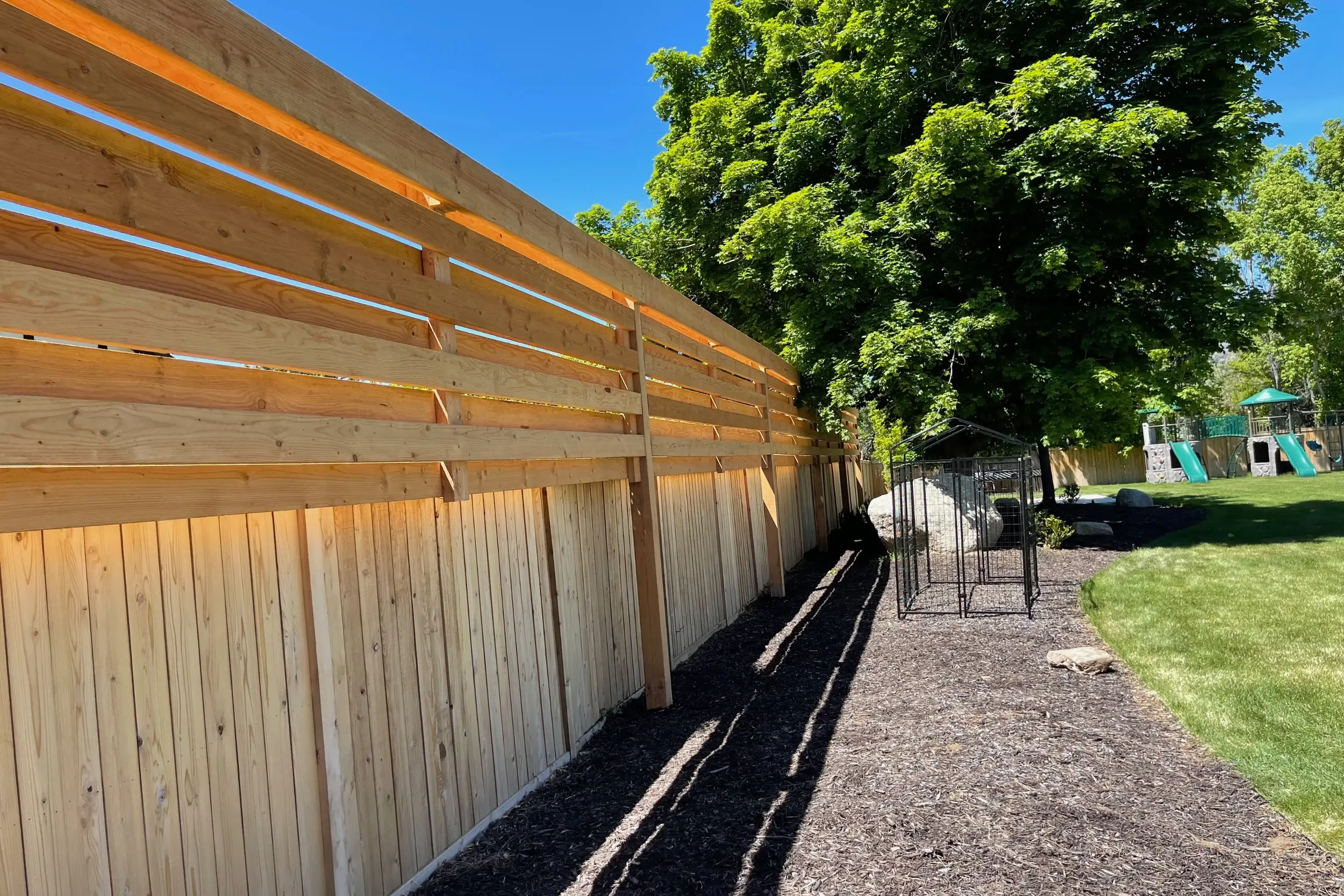 Wood trellis mounted above a privacy fence, ideal for the best plants for a wood trellis in a landscaped backyard.