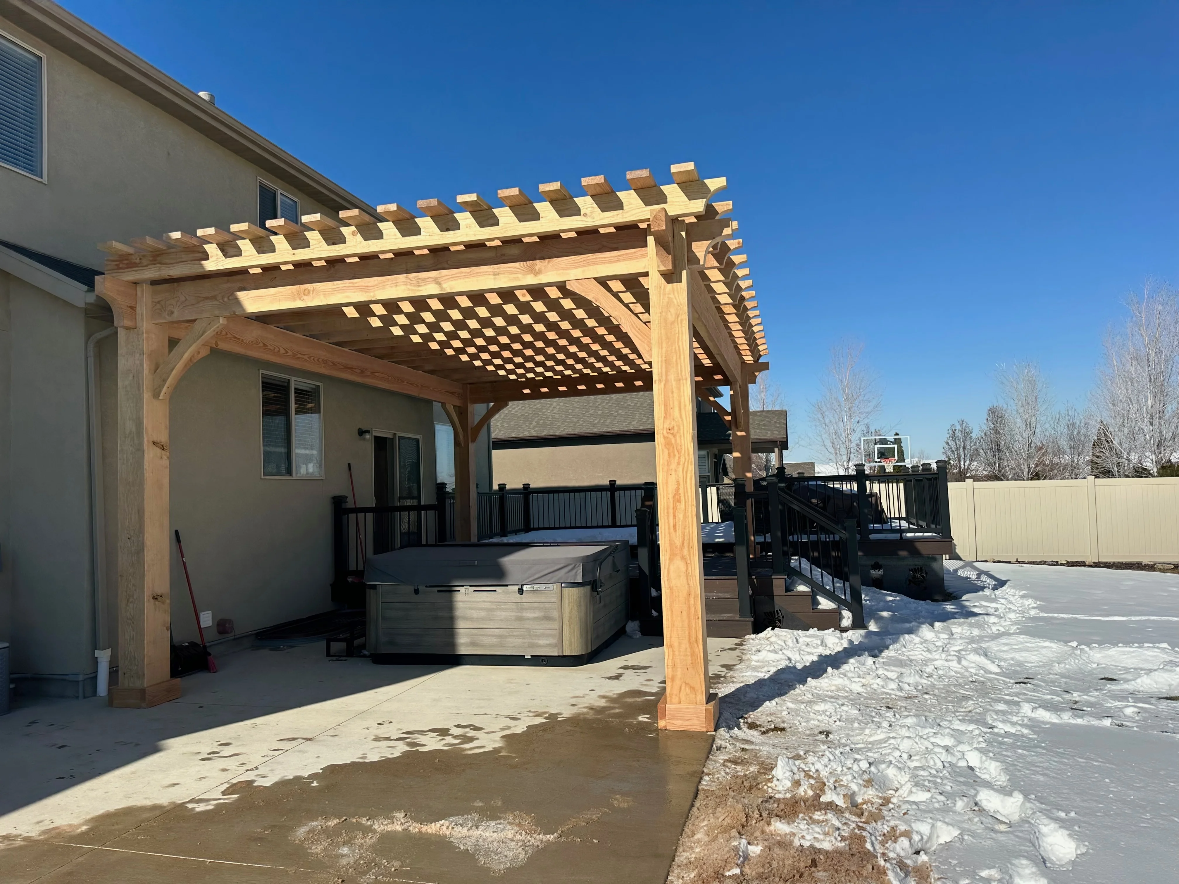 Timber pergola over hot tub with open rafters in winter.